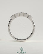 Emerald bezel set wedding band by Kynora CJ featuring a smooth gold ring with a central emerald gemstone.