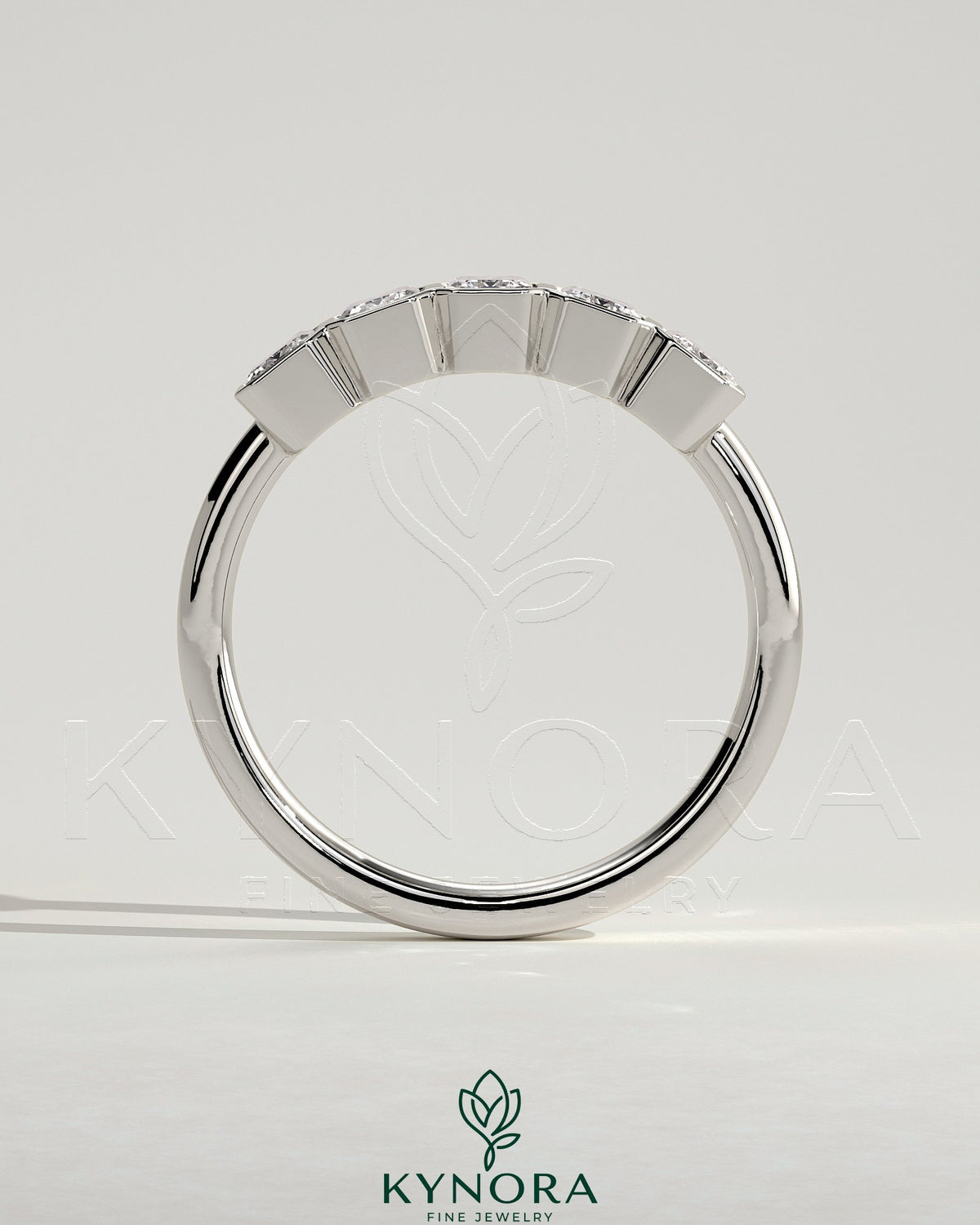 Emerald bezel set wedding band by Kynora CJ featuring a smooth gold ring with a central emerald gemstone.