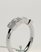 Emerald bezel set wedding band by Kynora CJ featuring a sleek gold design with a central emerald gemstone.