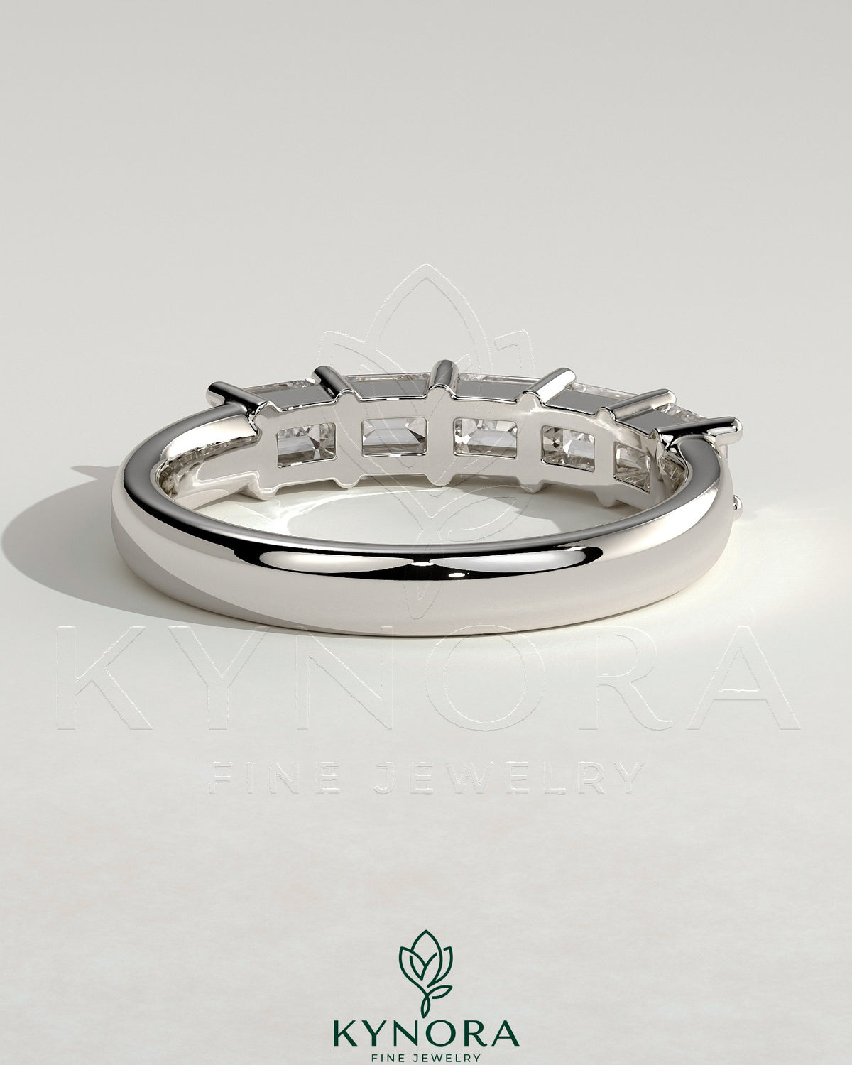 Kynora CJ emerald east-west wedding band with closed basket setting, featuring a central emerald gemstone and intricate metalwork.