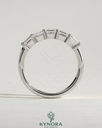 Kynora CJ emerald east-west accent wedding band with closed basket setting, featuring vibrant green emeralds and elegant gold band.