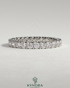 Kynora CJ full round eternity wedding band with scalloped setting, showcasing sparkling gemstones on a polished gold band.