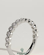 Kynora CJ half eternity wedding band with round bezel-set diamonds, showcasing a sleek and elegant design.