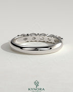 Kynora CJ sterling silver wedding band with oval east-west moissanite accent stone in closed basket setting.