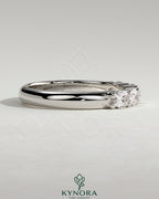 Sterling silver wedding band with oval east-west moissanite accent stone in a closed basket setting by Kynora CJ