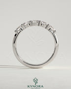 Kynora CJ sterling silver wedding band with oval east-west moissanite accent stone in closed basket setting.