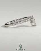Pear-shaped accent stone with curved pave band wedding ring by Kynora CJ, showcasing elegant jewelry design.