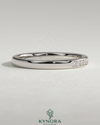 Kynora CJ round channel set wedding band with a sleek, polished finish, featuring a continuous row of gemstones on a silver-tone band.