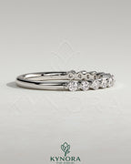 Round shared prong accent stone wedding band by Kynora CJ, featuring sparkling stones and a classic gold finish.