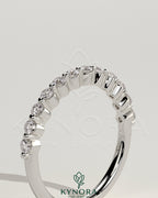 Round shared prong accent stone wedding ring by Kynora CJ, featuring sparkling gemstones on a sleek gold band.