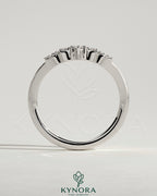 Close-up of Kynora CJ studded tiara curved pave band wedding ring with sparkling stones on a silver band.