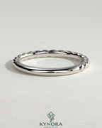 Elegant woven band wedding ring by Kynora CJ, showcasing intricate craftsmanship and a polished finish on a sleek gold band.