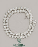 Sterling silver heart-shaped moissanite diamond halo tennis chain with 7mm VVS1 stones, crafted by Kynora Jewels.