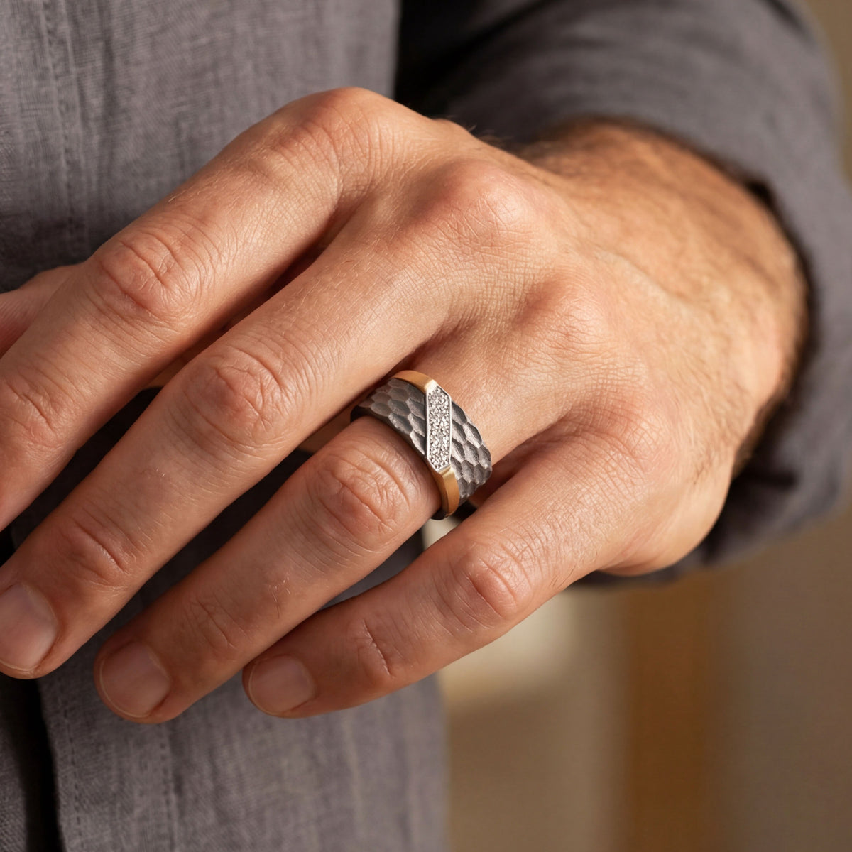 Men's titanium ring with diagonal pave moissanite and hammered 10k gold accents, showcasing a sleek, modern design.